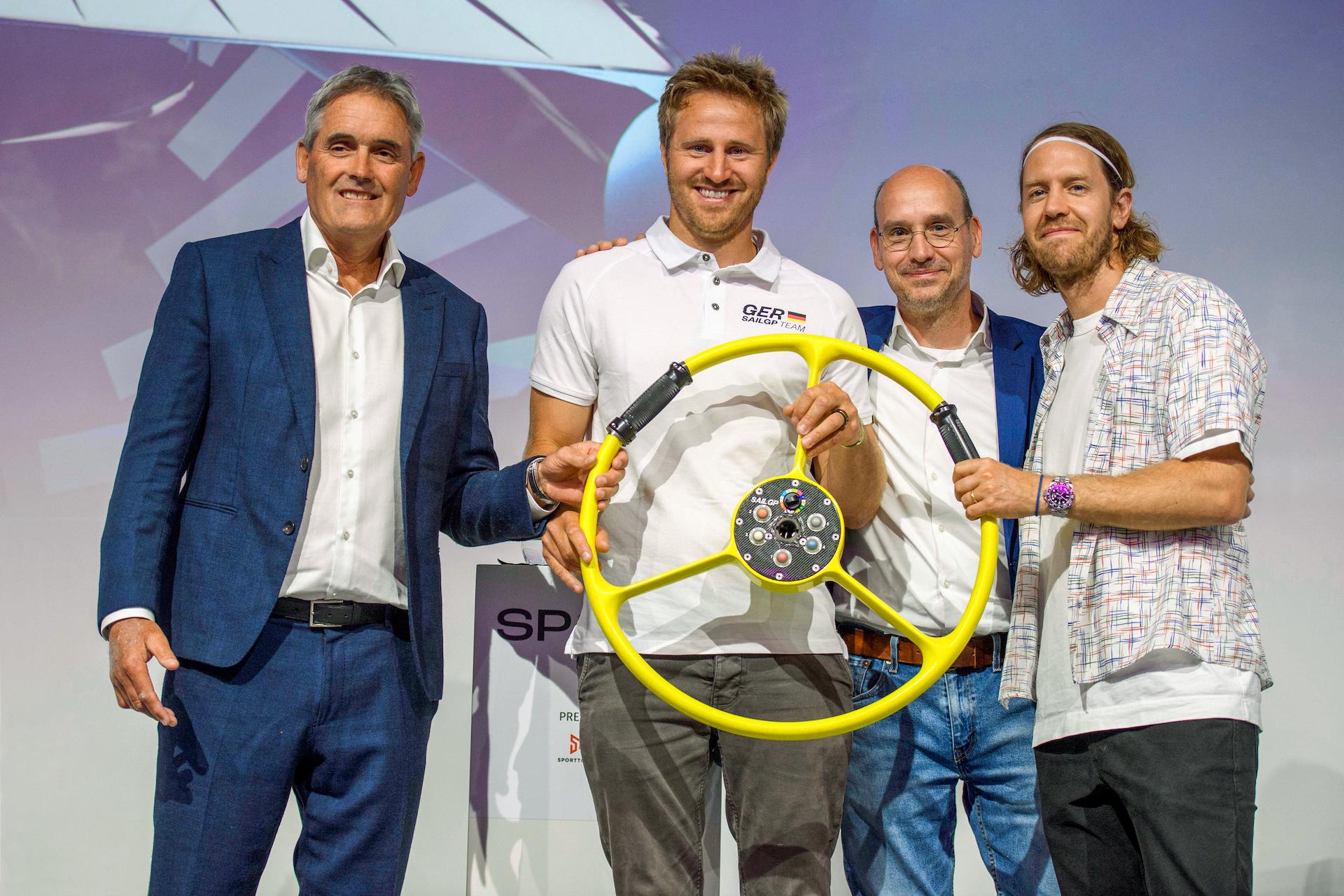 SailGP-Erfinder Russell Coutts übergibt das Steuer an Segler Erik Heil und die Investoren Thomas Riedel und Sebastian Vettel (v.l.n.r)