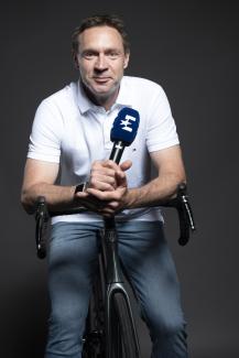 Jens Voigt mit Eurosport-Mikrofon auf einem Rennrad
